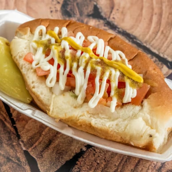 Sonoran hot dog from El Güero Canelo, topped with diced tomatoes, onions, mayonnaise, and mustard.